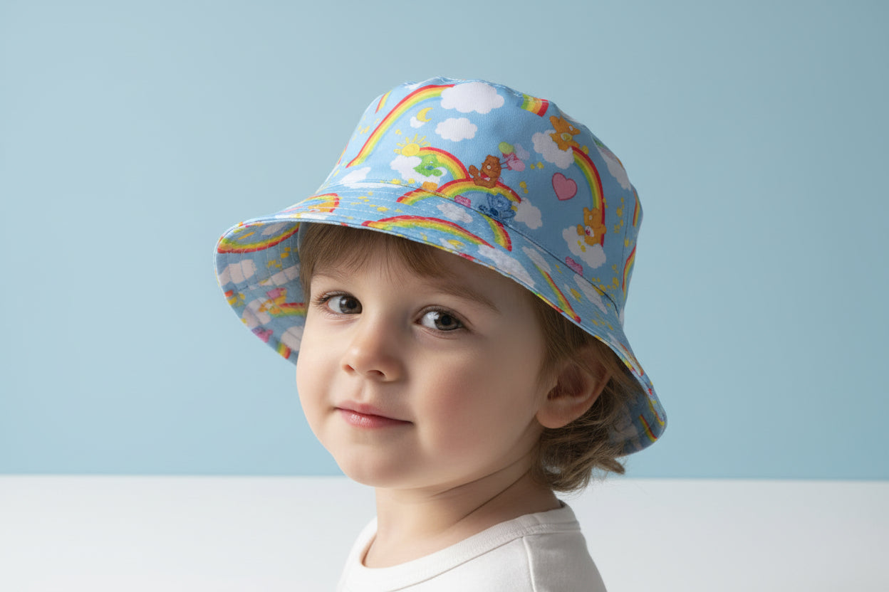 Child wearing a colorful bucket hat with rainbows and clouds against a light blue background