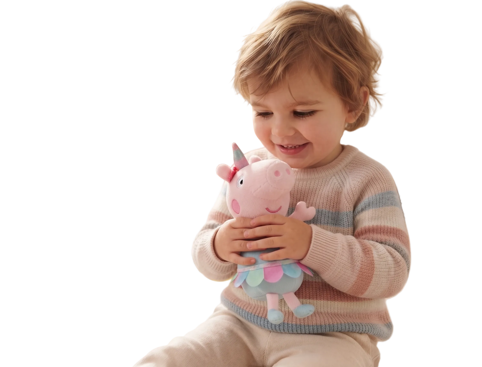 A young child sitting on a rug in a bright playroom, holding a pink plush toy with a unicorn horn and pastel wings. The child is wearing a striped knit sweater and cream pants, with toys and a sofa visible in the softly lit background.